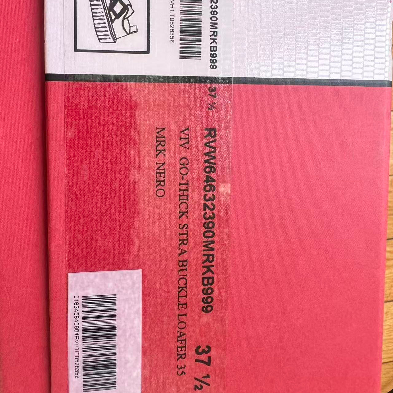 Red strap buckle lower with visible branding and barcode on a red background