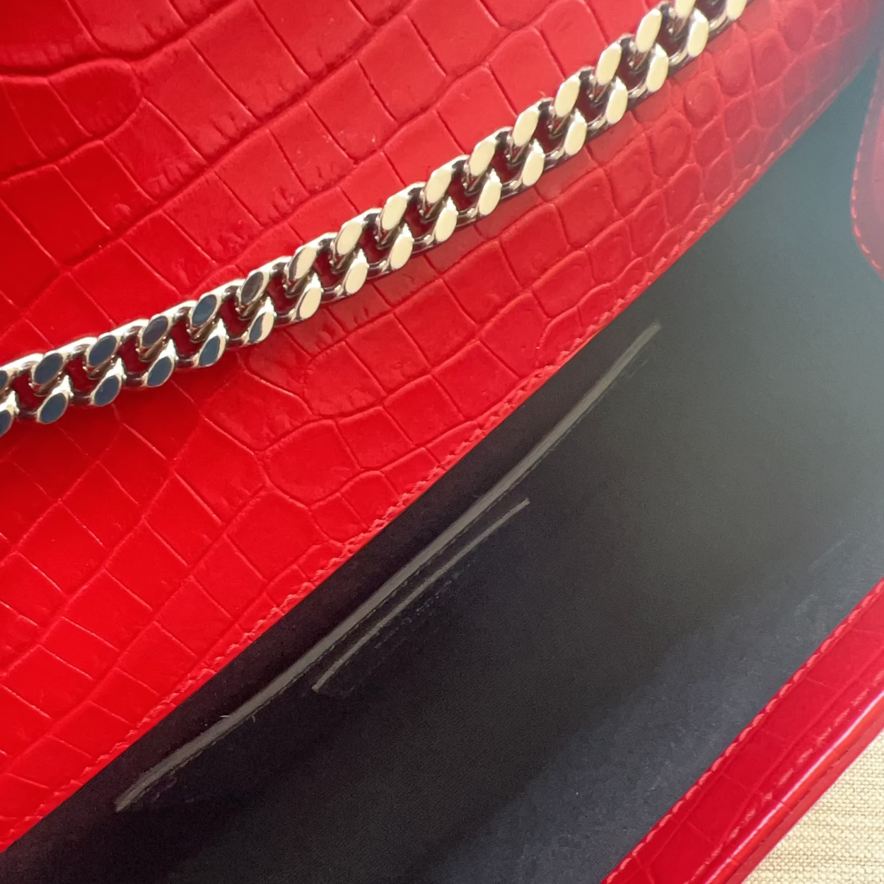 Close-up of a red textured handbag with a gold chain detail.