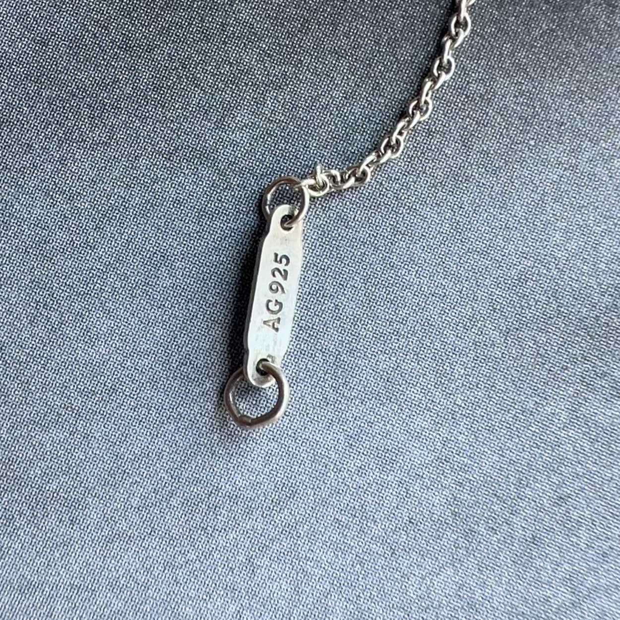 Silver necklace with a clasp on a gray fabric background