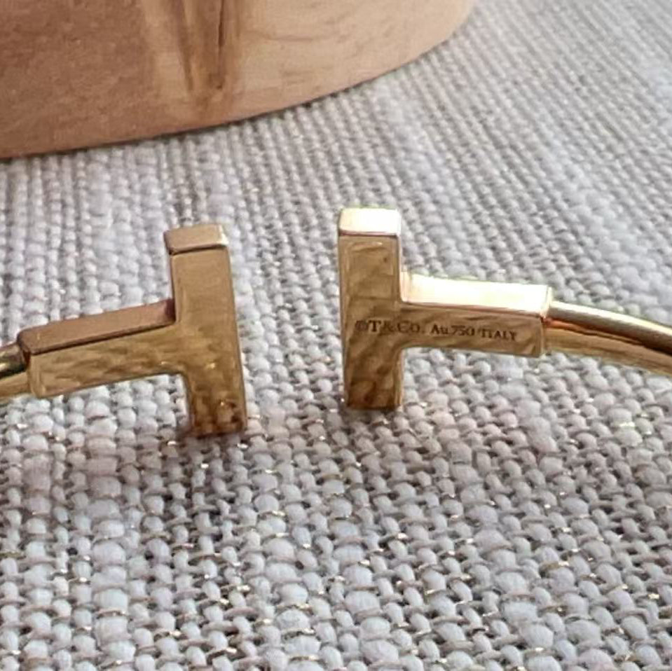 Gold bracelet with a brand name on a textured surface