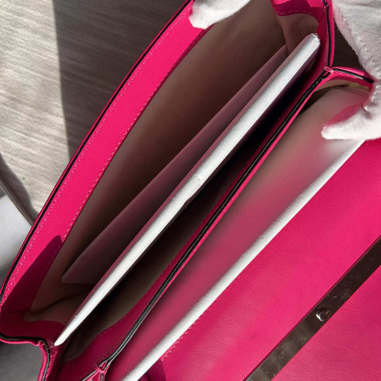 Pink handbag with a silver interior on a light gray surface