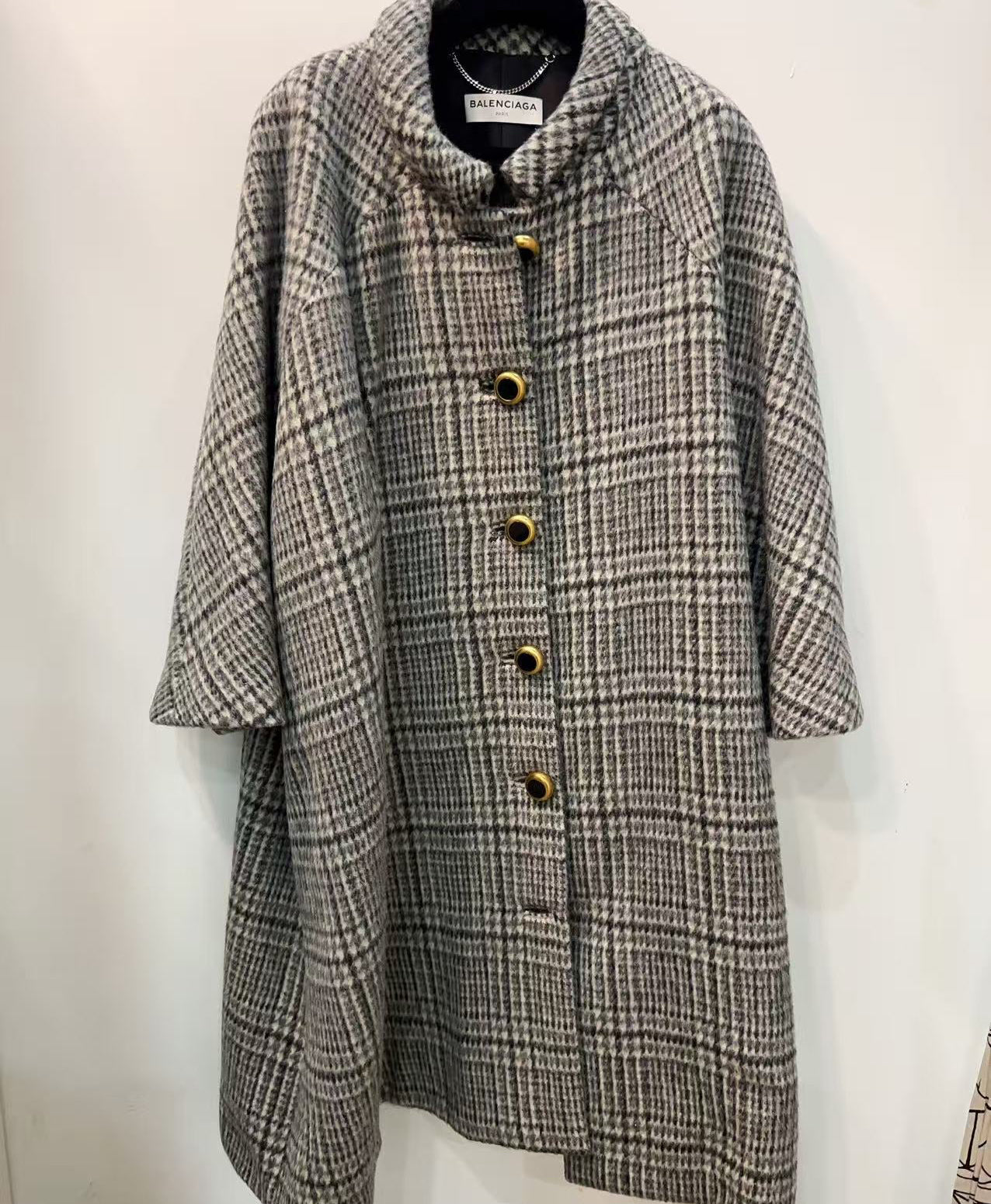 Plaid coat on a hanger against a white background