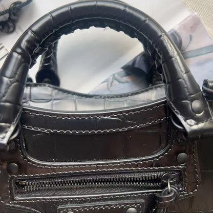 Close-up of a dark brown crocodile-embossed leather handbag showing the handle attachment, zipper, and stitching details.