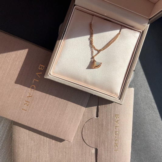 Rose gold necklace in a Balenciaga box on a textured surface