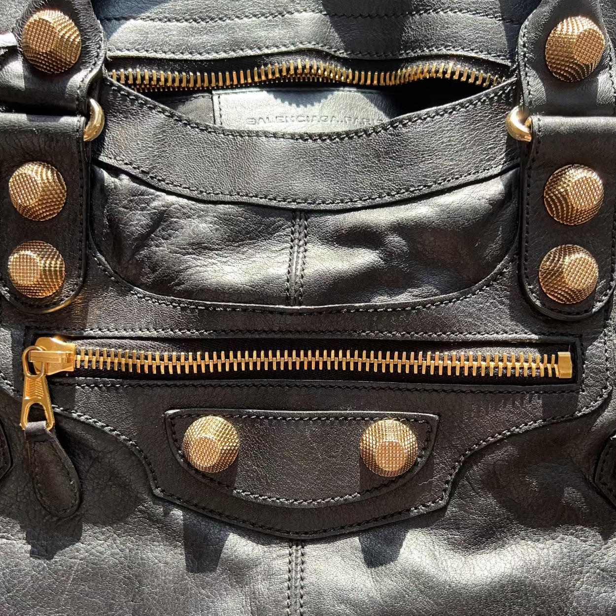 Close-up of a black leather jacket with gold zippers and studs