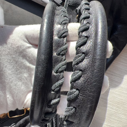 Close-up of a black sandal with braided design on a light-colored surface.