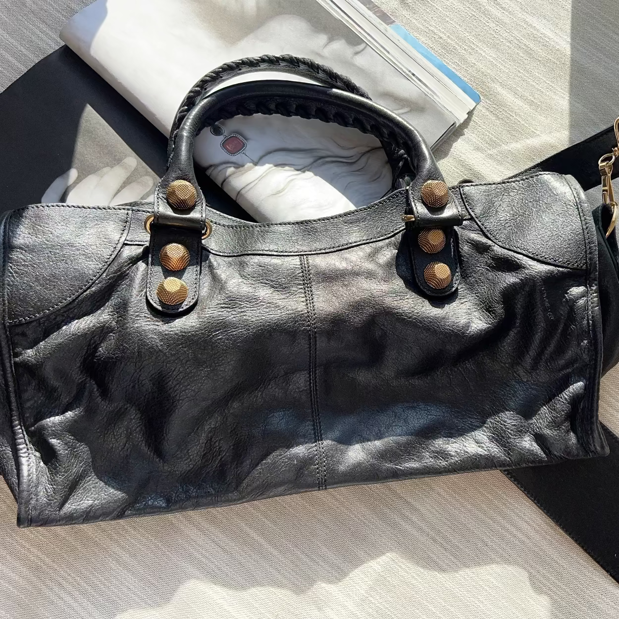 Black leather handbag with gold accents on a light wooden surface