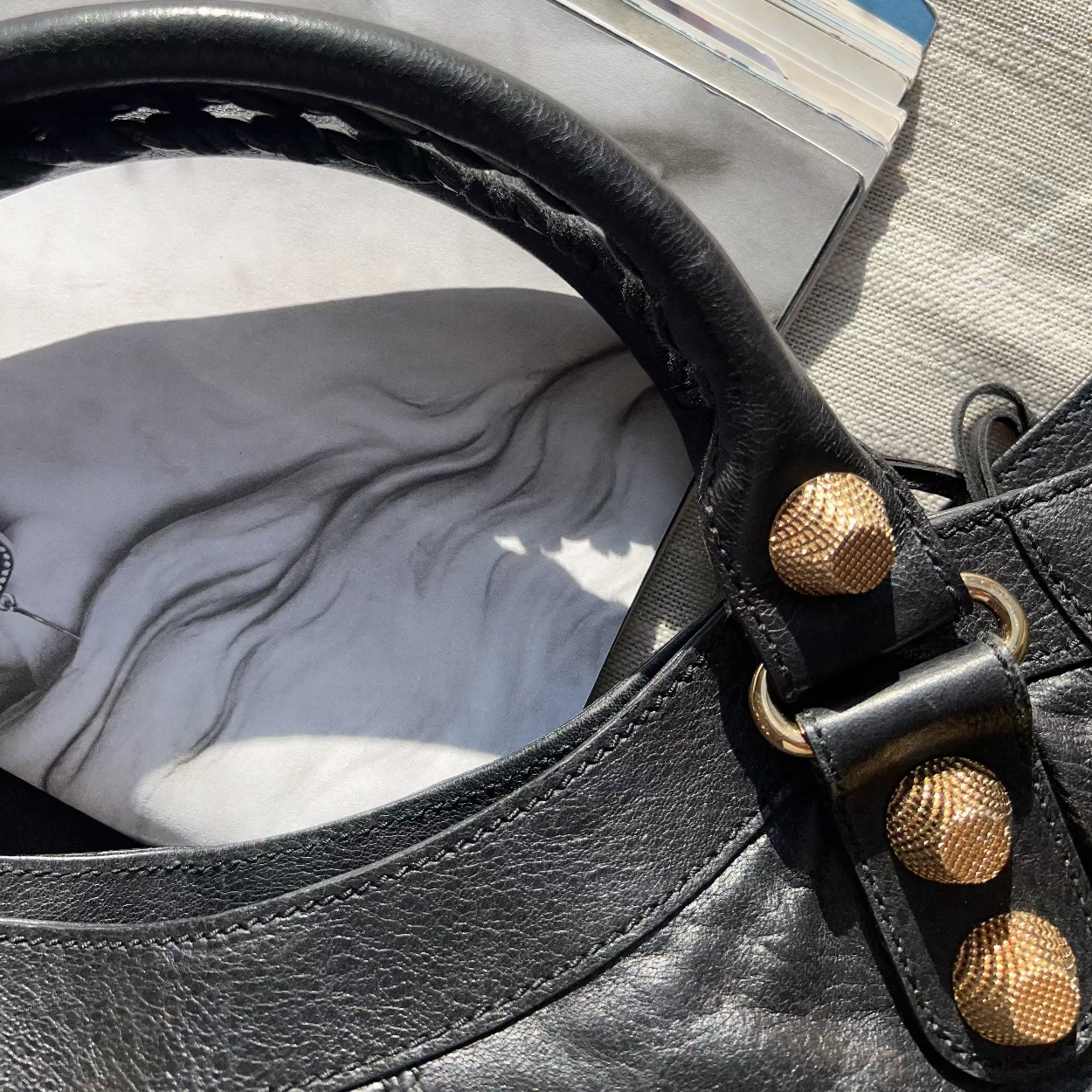 Close-up of a black leather bag with gold studs on a textured surface
