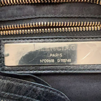 Close-up of a black fabric zippered pouch or bag interior with a central metallic silver tag showing the Balenciaga logo and serial numbers.