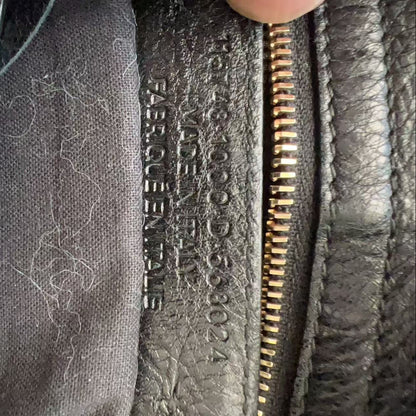 Close-up of a dark gray leather zipper pull with embossed text reading 'HERMÈS PARIS' and a gray fabric lining with visible lint.