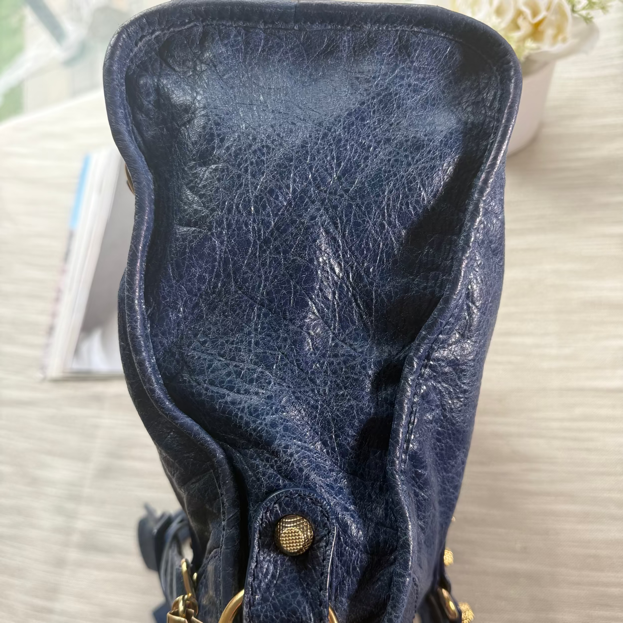 Blue leather bag with gold accents on a light surface
