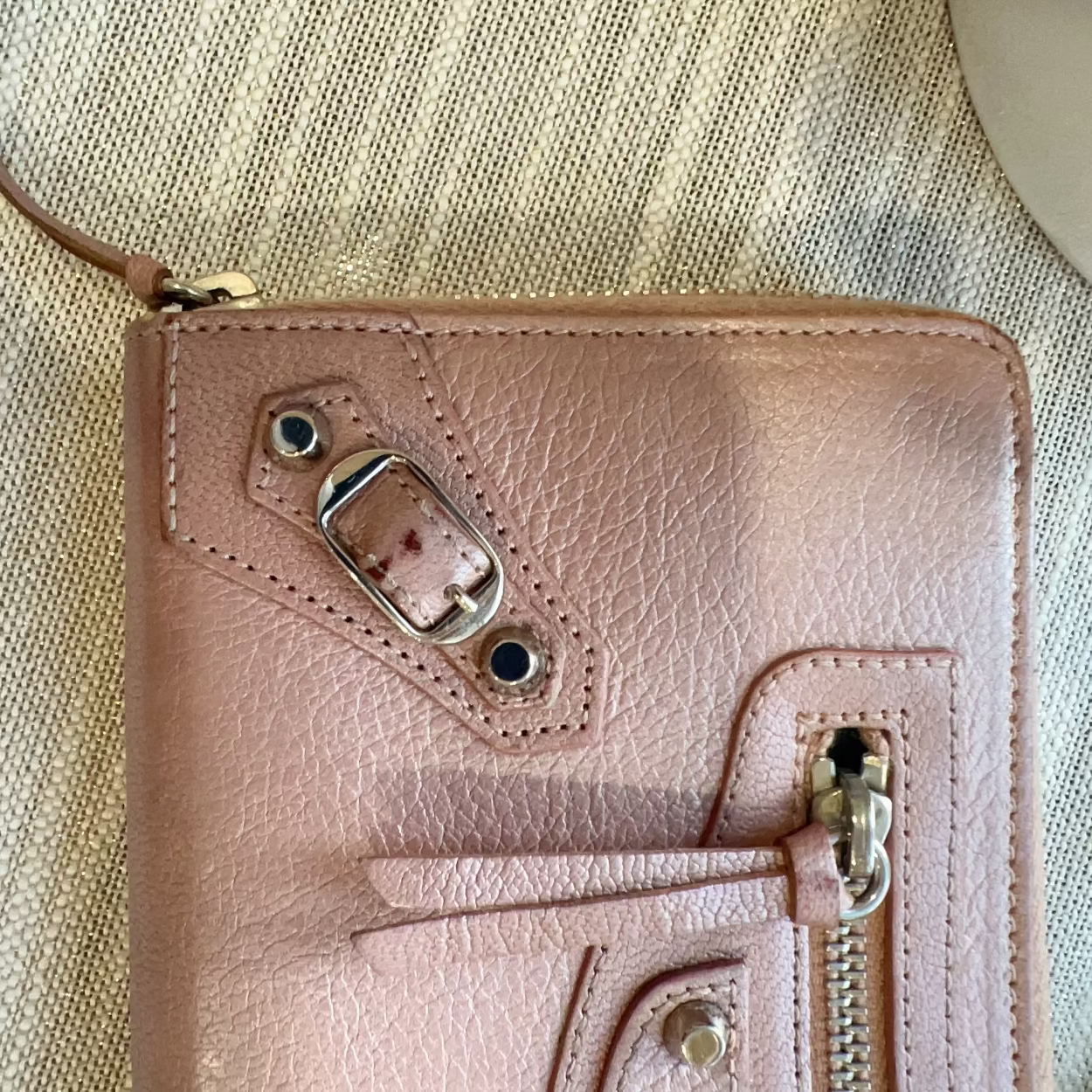 Pink leather wallet with metallic accents on a textured beige surface