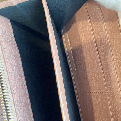 Close-up of a brown leather wallet with gold zipper and stitching detail.