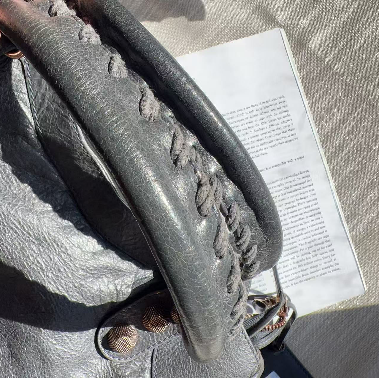 Gray textured handbag handle with gold accents 