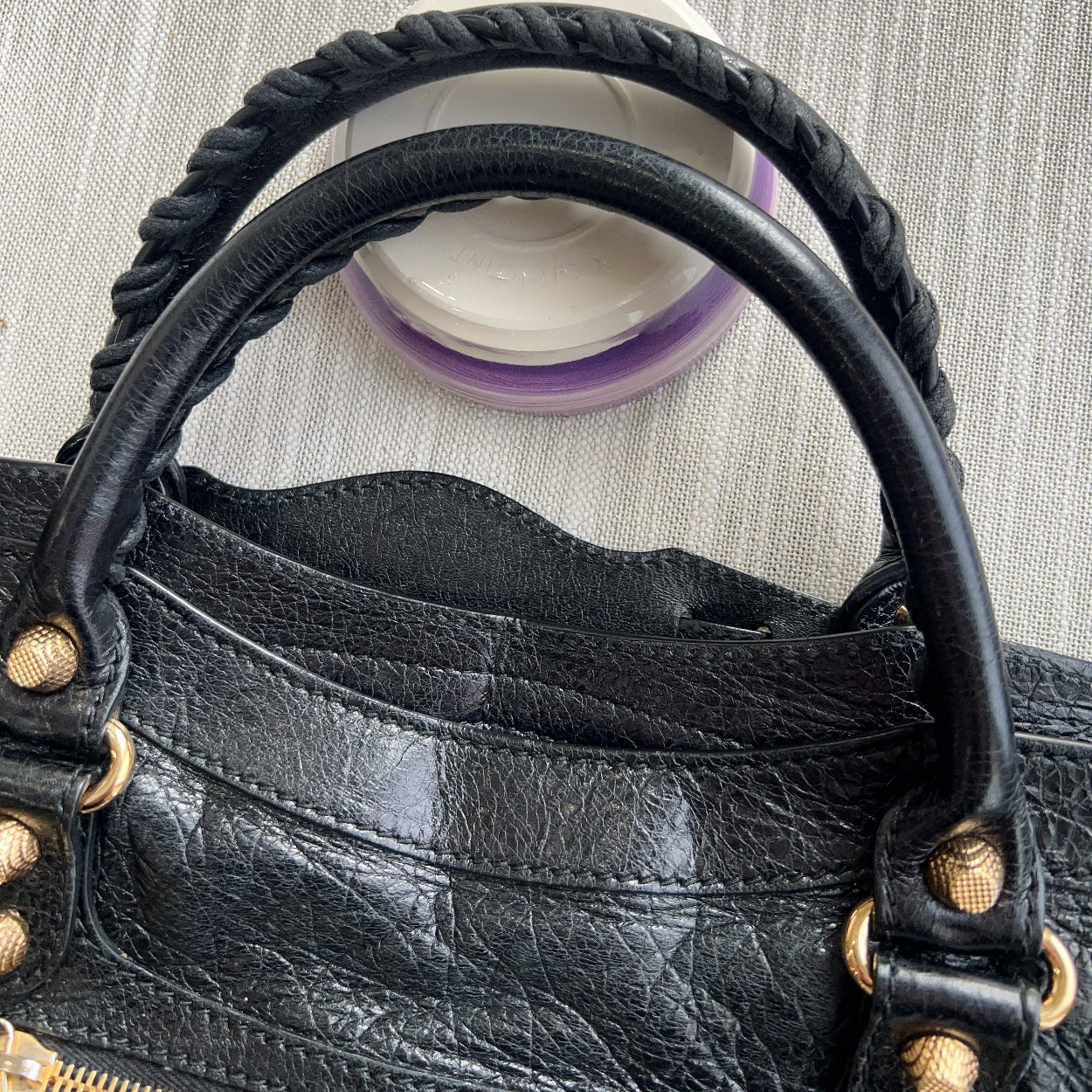 Black leather handbag with gold accents on a textured gray background