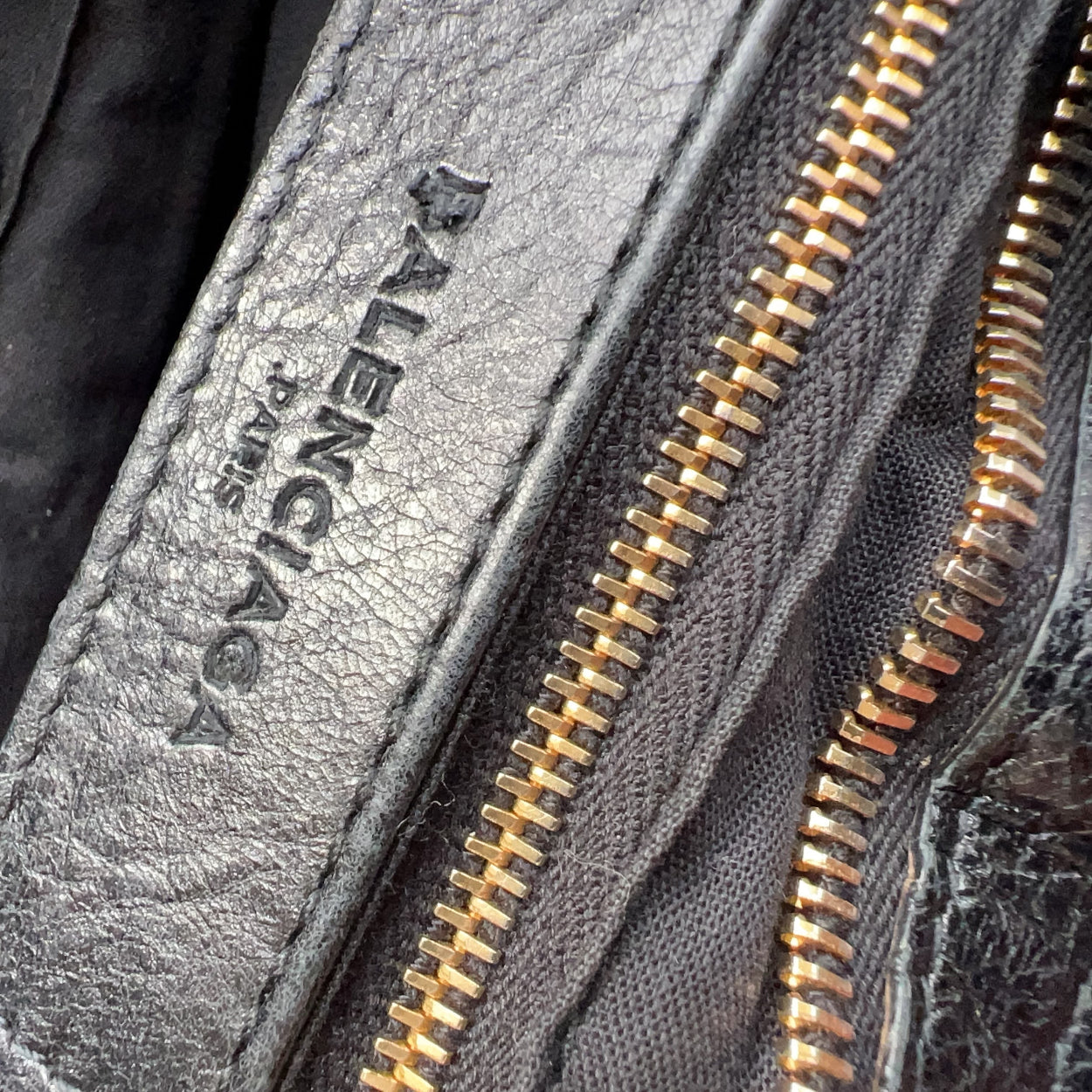 Close-up of a gray jacket with gold zipper and 'Valentino' branding.