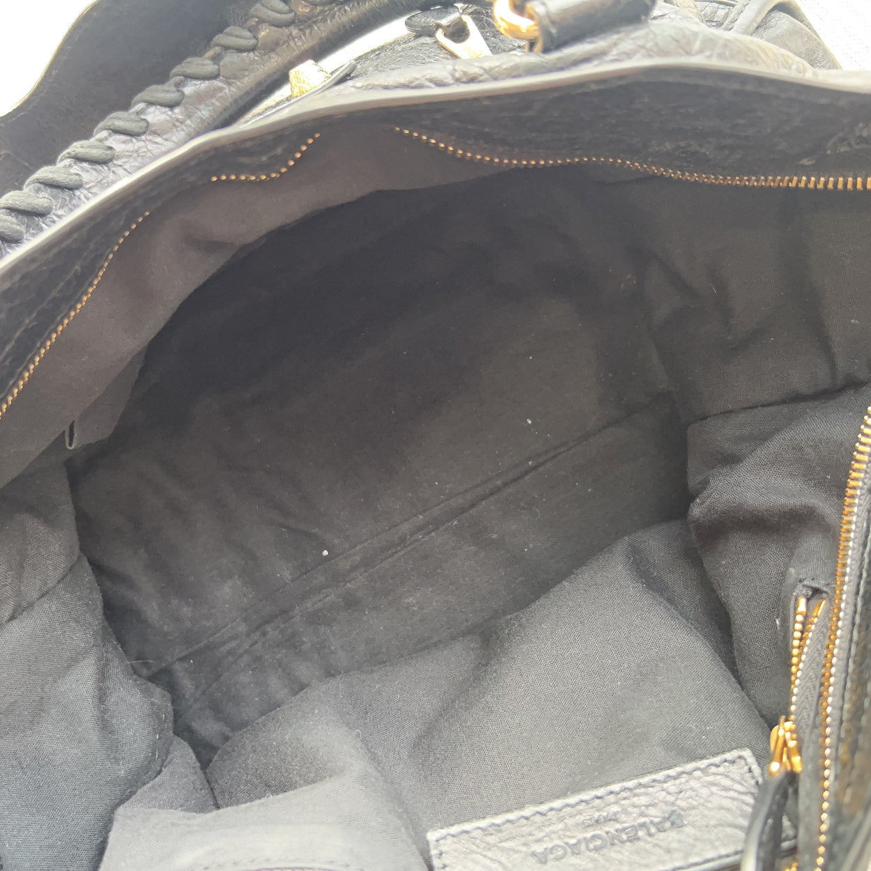 Close-up of a black leather bag with gold stitching