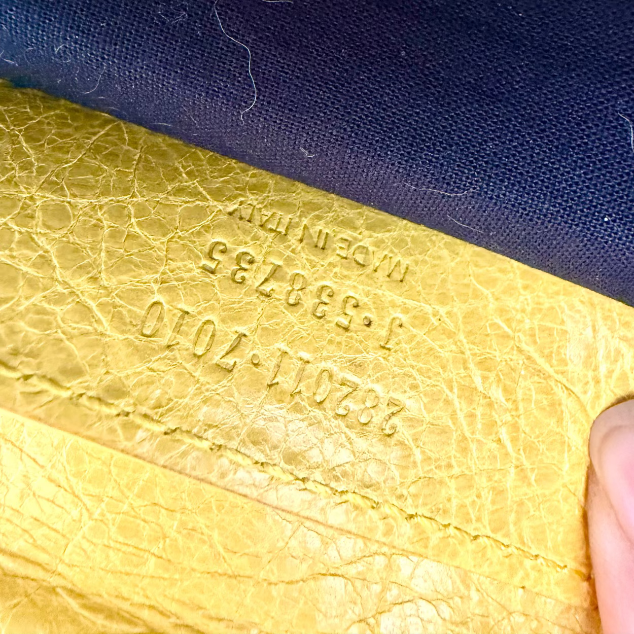 Close-up of a yellow leather item with embossed text against a dark blue background