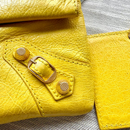 Close-up of a yellow leather wallet with a buckle on a textured surface