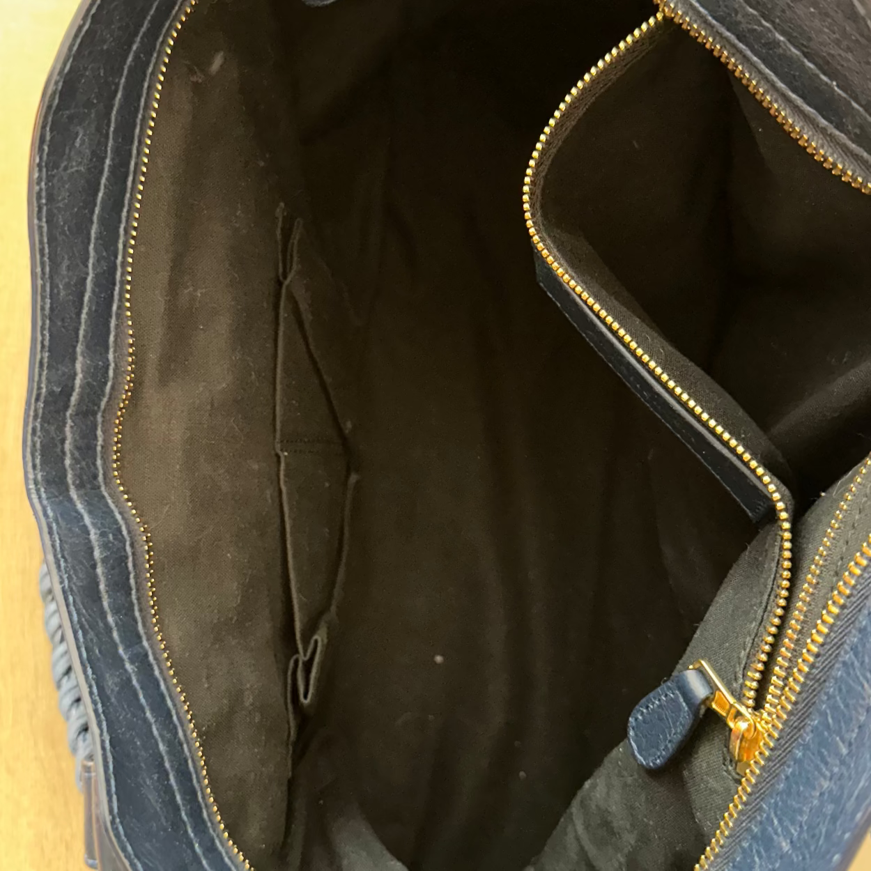 Open blue bag with gold zipper on a beige background