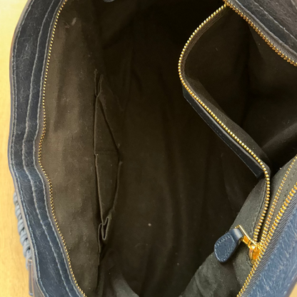 Open blue bag with gold zipper on a beige background