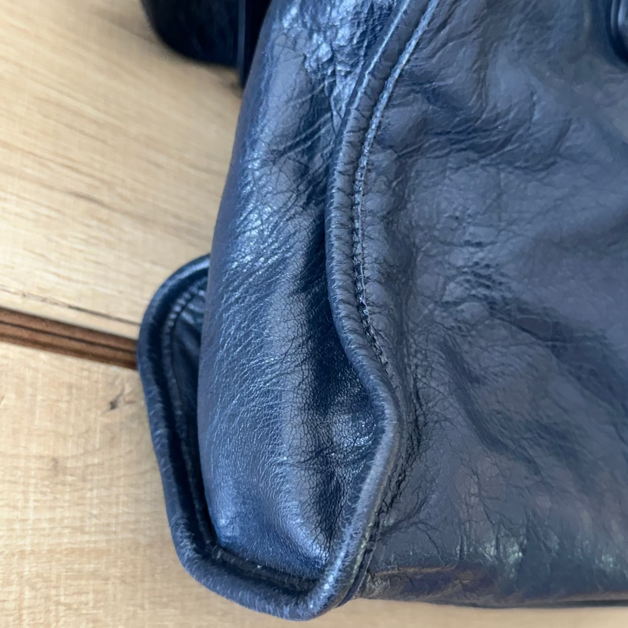 Close-up of a blue leather bag on a beige surface