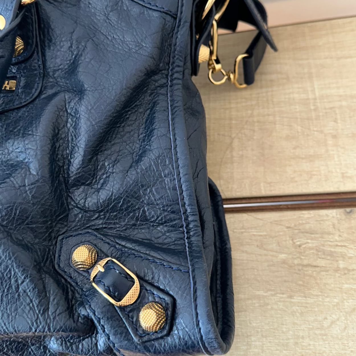 Blue leather handbag with gold hardware on a wooden surface