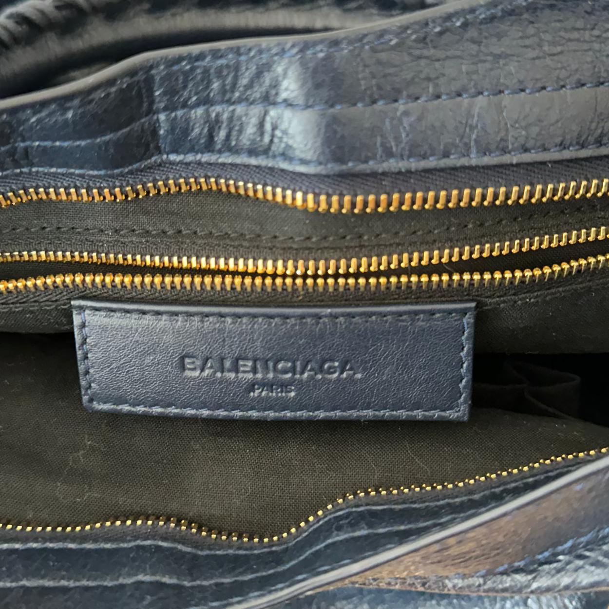 Close-up of a Balenciaga bag with gold zipper and visible brand logo.