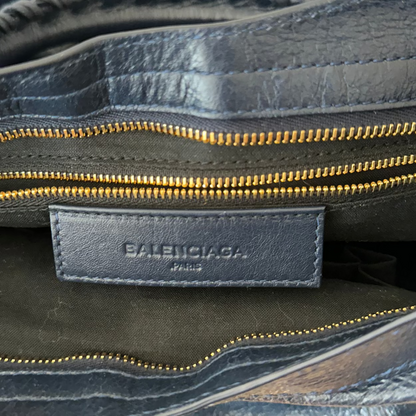 Close-up of a Balenciaga bag with gold zipper and visible brand logo.