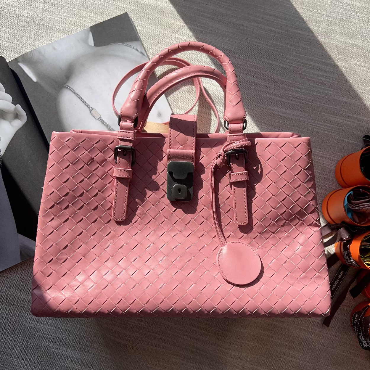 Pink woven handbag on a light wooden surface