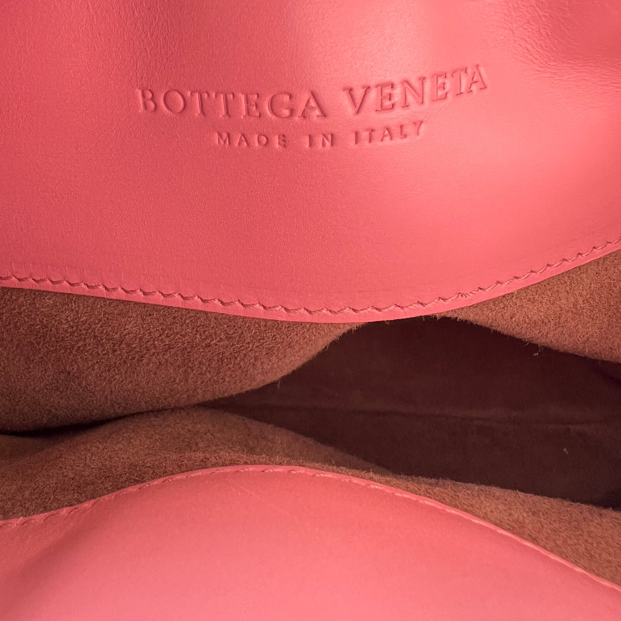 Close-up of Bottega Veneta logo on pink leather surface