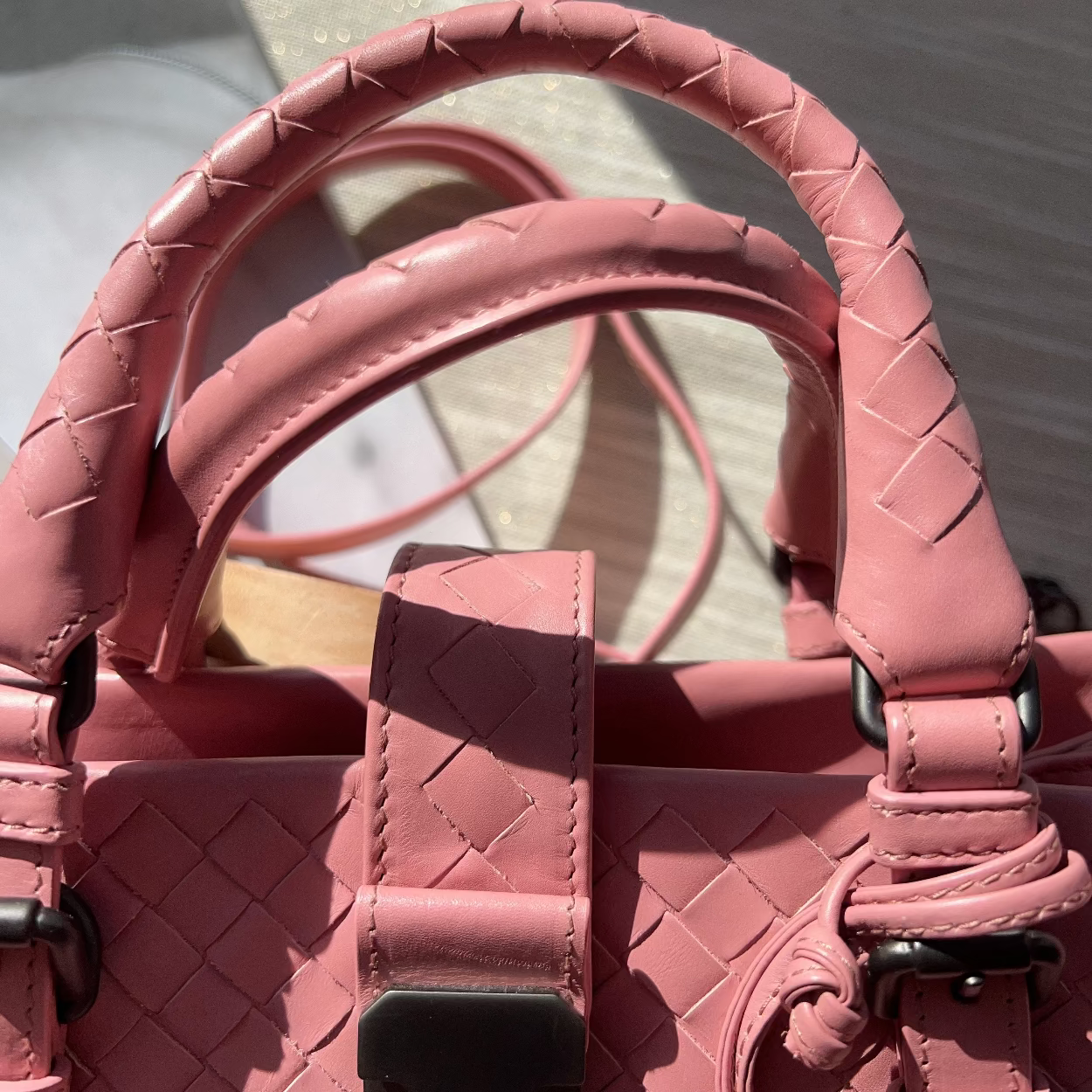 Pink handbag with textured handle and strap on a light background