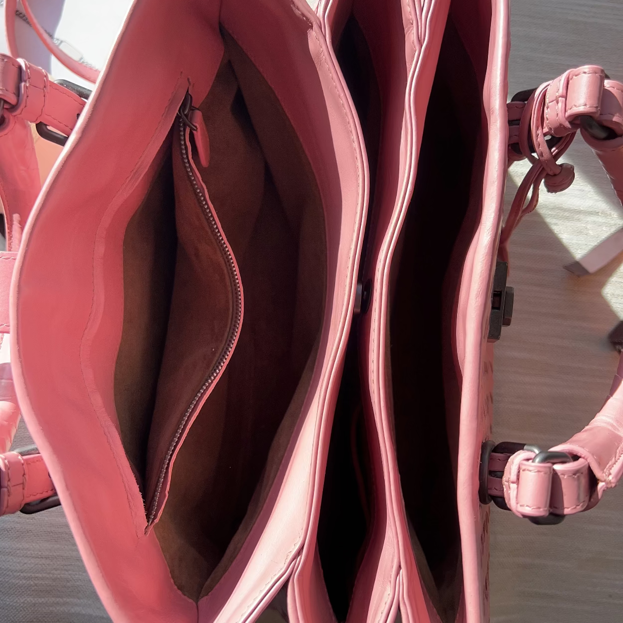Pink handbag with a strap on a wooden surface