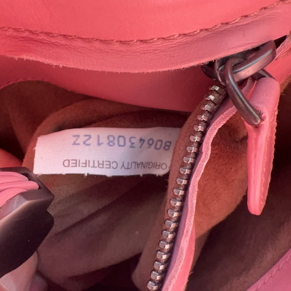 Close-up of a pink leather bag with a visible authenticity label.