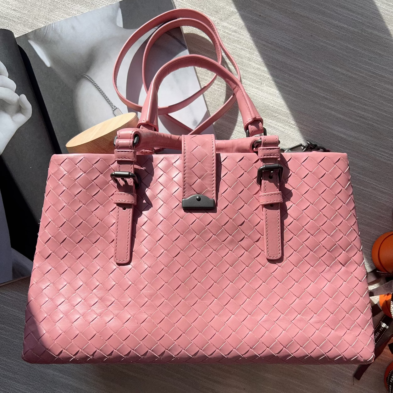Pink woven handbag on a light wooden surface