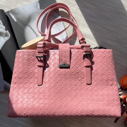 Pink woven handbag on a light wooden surface