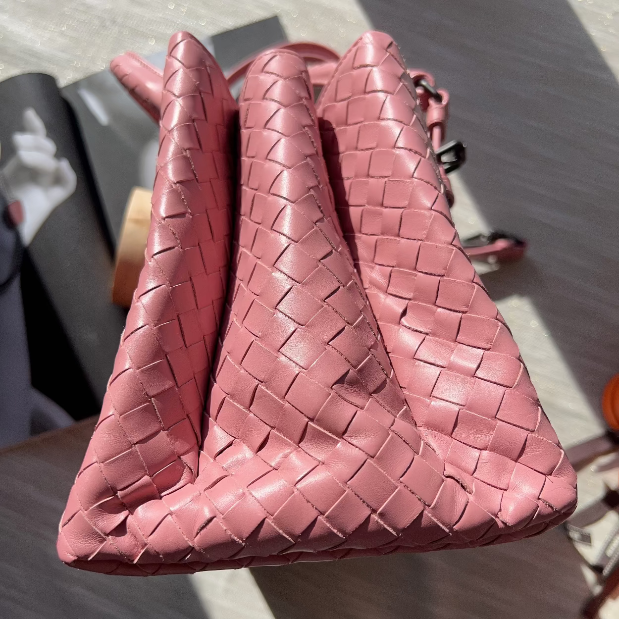 Pink woven handbag on a reflective surface