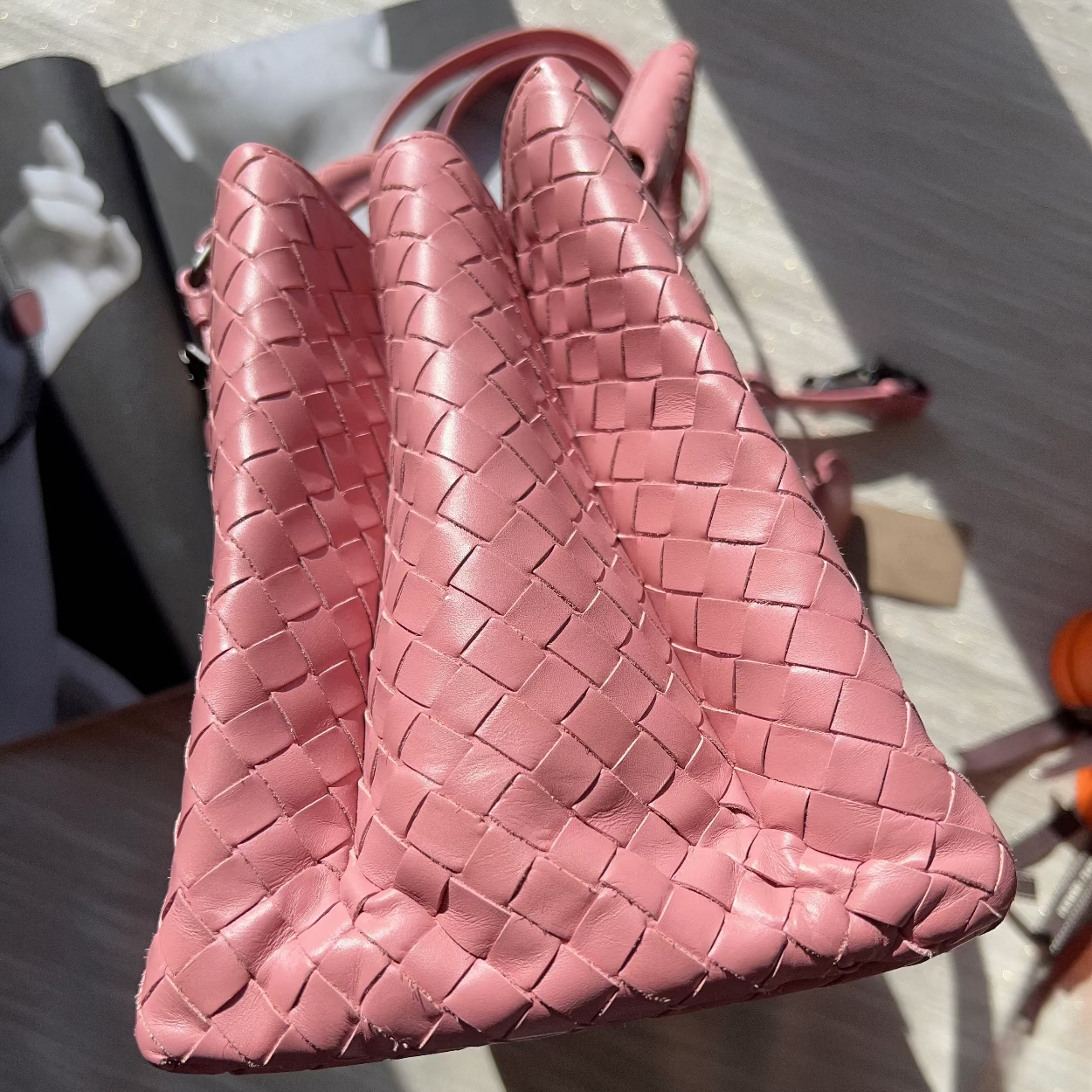 Pink woven handbag on a textured surface
