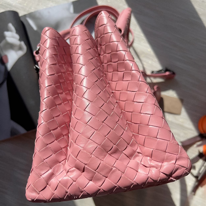 Pink woven handbag on a textured surface