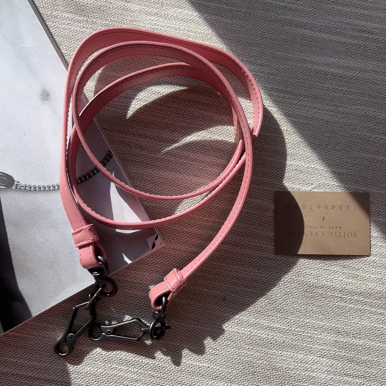 Pink leather dog leash with a metal clip on a textured surface