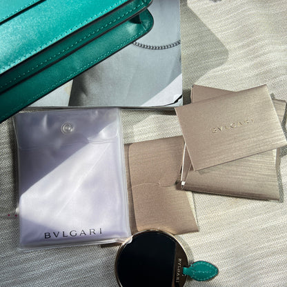 Collage of luxury items including a Bulgari bag, sunglasses, and a Bvlgari box on a textured surface.
