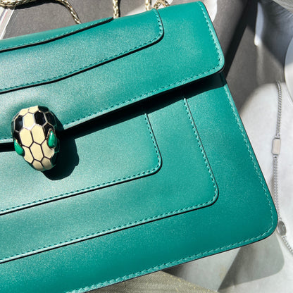 Teal handbag with a decorative clasp on a neutral background