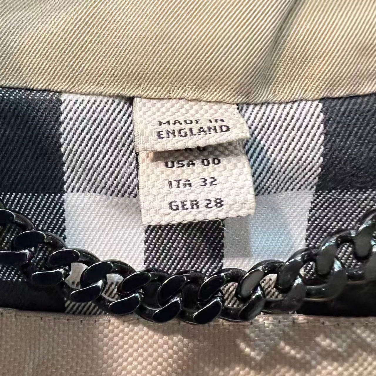 Close-up of a label on a plaid fabric with a chain detail.