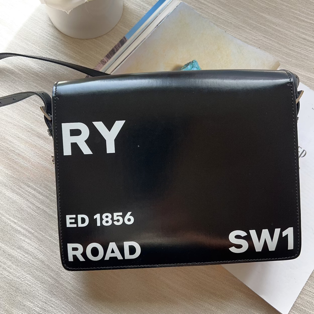 Black handbag with text on a light wooden surface