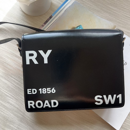 Black handbag with text on a light wooden surface