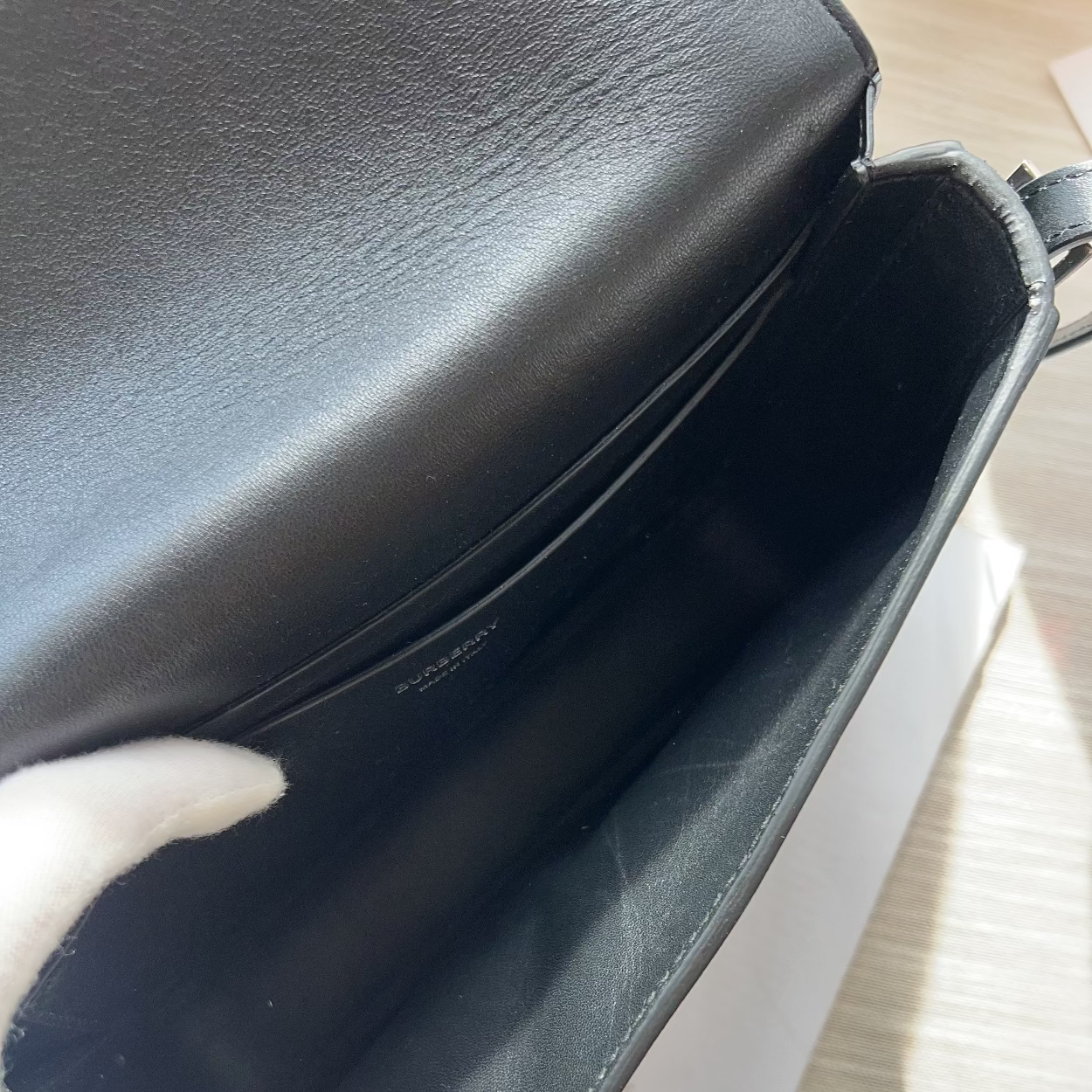 Close-up of a black leather handbag on a light wooden surface.