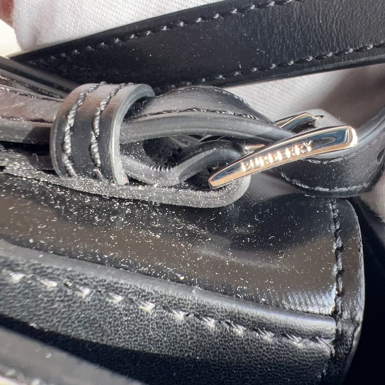 Close-up of a black leather bag with a gold zipper, held by a gloved hand.