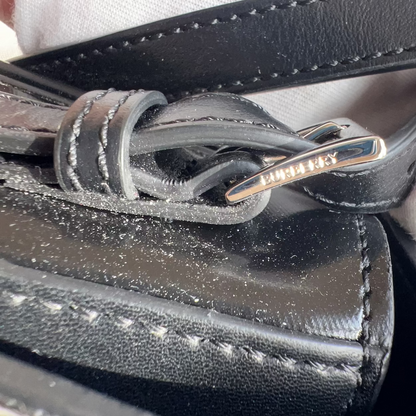 Close-up of a black leather bag with a gold zipper, held by a gloved hand.