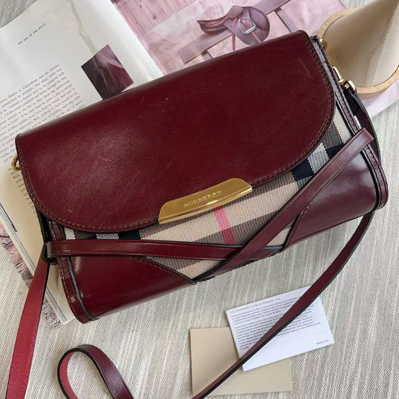 Brown leather handbag with a visible brand logo on a surface with papers underneath