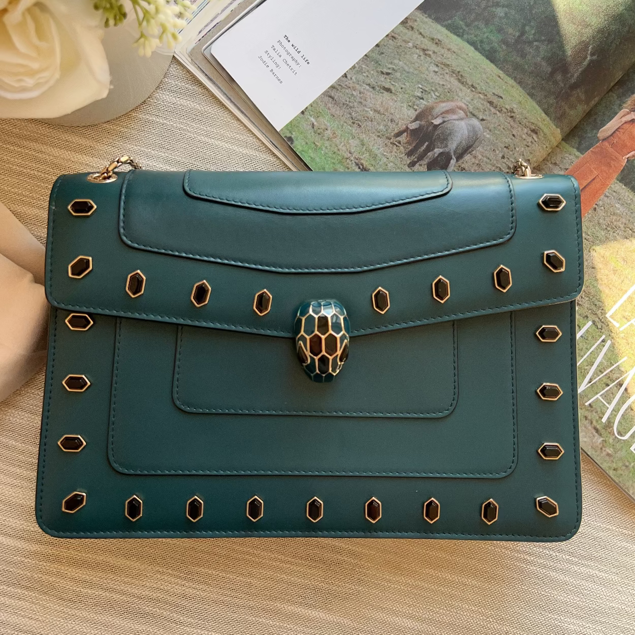 Green handbag with decorative studs on a wooden surface